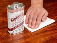 A person applies FloorFil Solvent to a scratched floor.