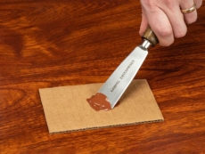 A person mixes FloorFil laminate floor repair/filler with a putty knife.